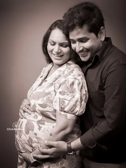A beautiful moment of togetherness, captured in a warm sepia tone. This classic portrait shows the couple embracing, their smiles reflecting the shared happiness of their pregnancy journey.