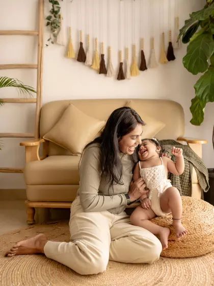 A mother and daughter play together on the floor. The baby's unrestrained laughter is the highlight of this incredibly joyful and candid shot.