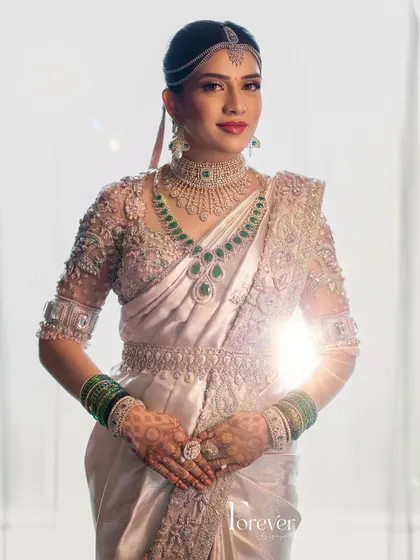 The bride stands radiant in the sunlight. Her custom-designed saree with a matching blouse and veil is a masterpiece of bridal couture.