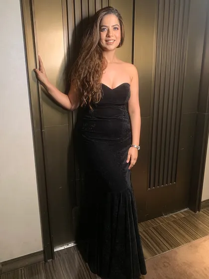 A final full-length pose in the black velvet gown, showcasing its classic and elegant silhouette.