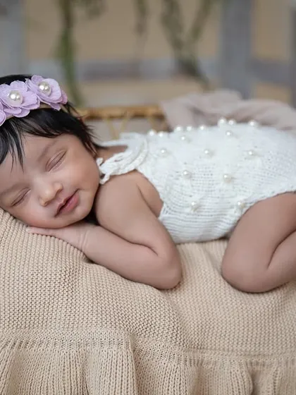 A sweet smile from a sleeping newborn is pure magic. This little girl, with a delicate floral headband, is dreaming peacefully during her studio session.