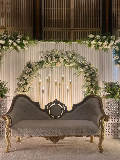 Another angle of the serene white-on-white stage decor. The clean lines of the backdrop and the lushness of the floral arrangements create a look of understated luxury.