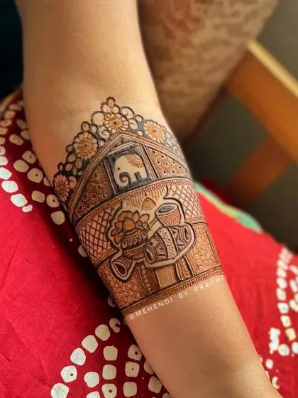 This bridal armband features classic wedding elements. You can see the 'dhol' (drum), 'shehnaai' (flute), and 'kalash' (pot), all symbols of a joyous celebration.