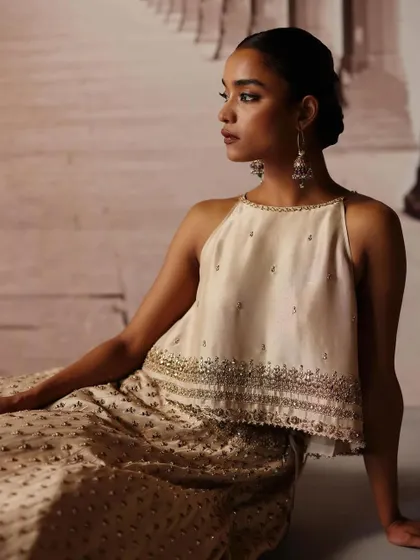 A close-up on a halter-neck blouse with delicate embroidery. The styling is focused on creating a refined and modern look, complemented by subtle, elegant jewelry.