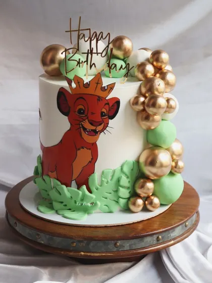 A fun take on the Lion King theme, this cake features a crowned Simba. The design is completed with a cascade of green and gold spheres to represent the jungle vibe.