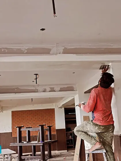 A painter applying putty to a false ceiling to prepare it for painting. This step ensures that all joints and imperfections are hidden, resulting in a perfectly smooth ceiling.
