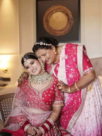 A vision in red. This bride shares a tender moment with her mother, her soft glam makeup and radiant smile capturing the joy of the day.