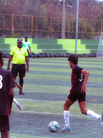 A player controls the ball under the watchful eye of the referee during a U-13 YPL game.