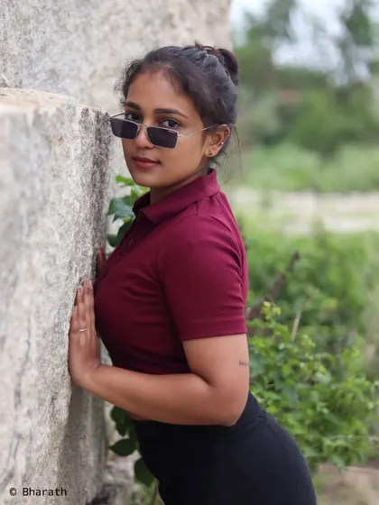 A confident portrait against a large rock, using sunglasses as a prop to add style and attitude.