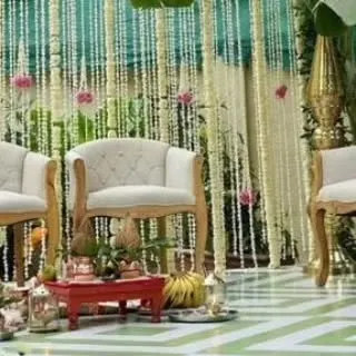 This image shows the seating arrangement within a traditional mandap. The elegant chairs are set against a backdrop of hanging floral strings, creating a beautiful and authentic ceremony space.
