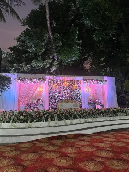 The reception stage at dusk, where our lighting design begins to transform the atmosphere, making the floral wall and chandeliers glow.