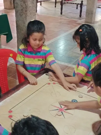 Students enjoy a game of carrom during their field trip, a great activity for developing focus and strategic thinking.