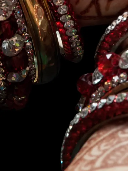 A close-up of traditional red and white bridal bangles (chooda). These details are an essential part of the bride's look, and we ensure every element is perfect.