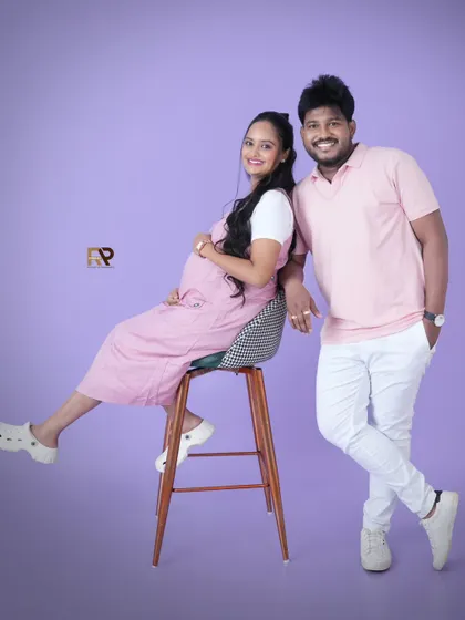 A fun and casual couple's portrait. The parents-to-be are coordinated in pink and white, creating a light, airy, and joyful photo that perfectly captures their personalities.