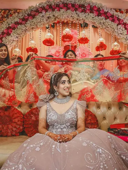 A traditional moment during the ring ceremony, where the bride is seated under a decorative chunni held by her family.