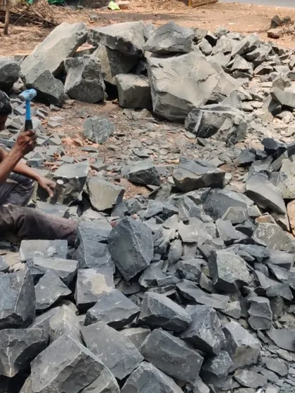A close-up of a worker using a hammer and chisel to dress raw stone. This traditional technique requires immense skill and patience, resulting in unique textures that cannot be replicated by machines.