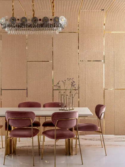 The dining area is the heart of the home, enveloped in soft, clay-textured paneling on the walls and ceiling. A sculptural chandelier and plush velvet chairs create a space that is inviting, luxurious, and minimal.