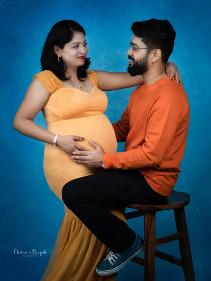 A vibrant and loving portrait. The contrast between her yellow dress and his orange sweater against the blue background is stunning.