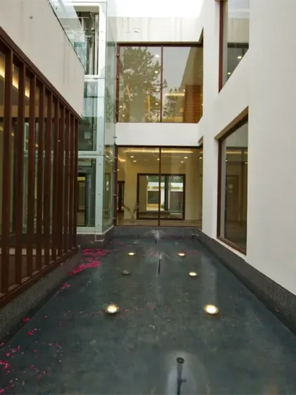 The glass lift at Sachdeva Farmhouse is anchored within a serene water body. The surrounding lobby and corridor areas open their views into this tranquil feature, bringing nature into the heart of the home.