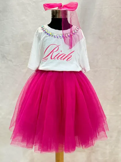 This custom birthday outfit is all about personal touches. The t-shirt features her name, "Riah," and a sparkling neckline, perfectly complementing the vibrant pink tulle skirt and matching hair accessory.
