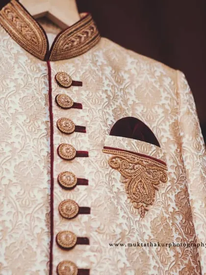 A close-up of the brocade fabric and button details on the groom's wedding outfit.