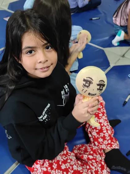 Another student proudly displays the puppet she made and decorated herself during our workshop for international school children.