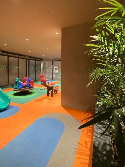 The flowing, colorful graphics on the rubber flooring create a sense of energy and openness, turning a simple concrete space into a vibrant play-scape.