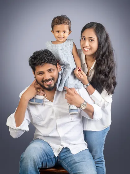 A fun and loving family pose. With their daughter on dad's shoulders, this family portrait is full of happiness and connection.