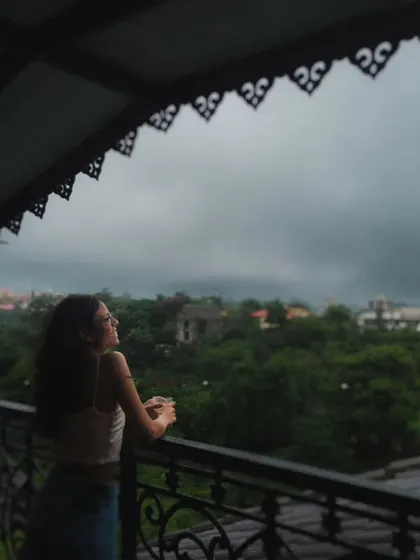 A quiet moment on a balcony overlooking the lush greenery of a monsoon getaway. This shot captures the peaceful, romantic mood of escaping the city for the rains.