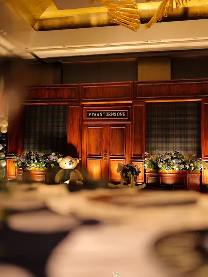 An artistic shot looking across a detailed tablescape towards the main stage. This perspective highlights the layers of our design, from the foreground details to the grand backdrop of this special first birthday.