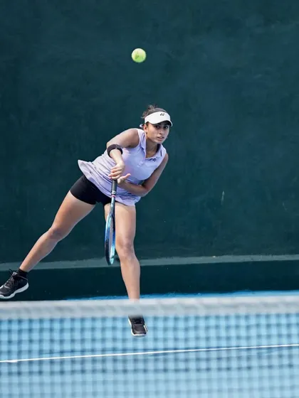 A player caught at the peak of her service motion, demonstrating the power and athleticism developed through our strength and conditioning programs.