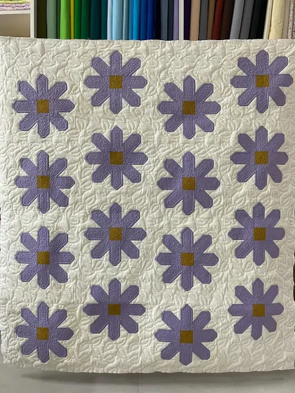 A lovely "Daisy" quilt with simple purple flowers against a white background. The leaf-like quilting adds a beautiful finishing touch.