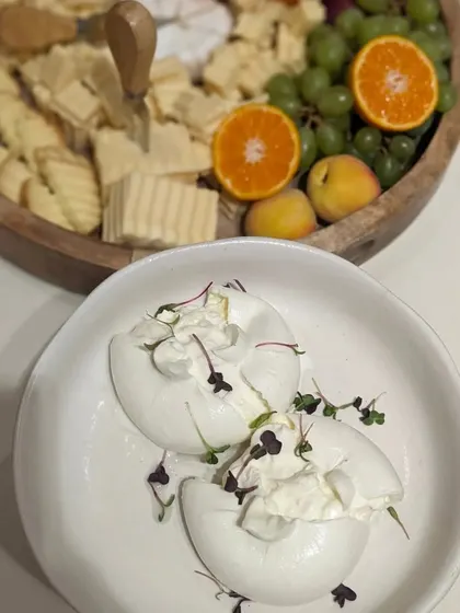 Freshly prepared burrata, ready to be served alongside a platter of assorted cheeses and fruits. The creamy interior of the burrata is always a showstopper.