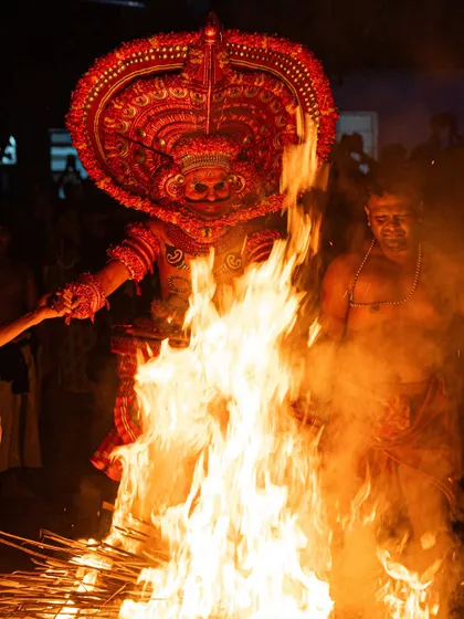 Close-up and action shots of the Kandanar Kelan Theyyam, focusing on the detailed costume, expressive mask, and the raw power of the fire performance.