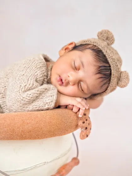 A sleepy little teddy bear snoozing in a bucket. The knitted bear hat and outfit are some of my favorite props for a cozy and cute session.