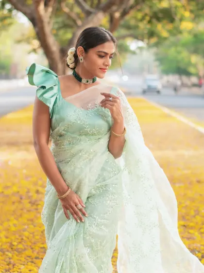 A model wearing a light green organza saree with a statement ruffled sleeve blouse. This is a perfect example of my custom blouse design service.