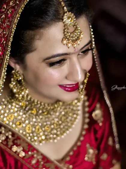 A close-up shot capturing the bride's flawless makeup and the intricate details of her maang tikka.