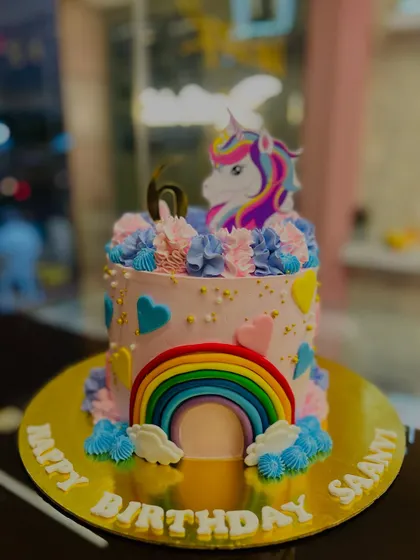 A closer look at the magical unicorn cake, showing the details of the rainbow and the unicorn topper.