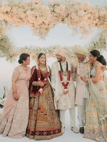 A beautiful family portrait of Rahul and Pallavi with their parents on the wedding stage in Thailand. This image captures the union of two families with the stunning ocean view behind them.