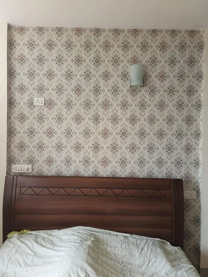A subtle, small-print damask wallpaper used as a bedroom accent wall.