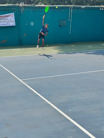 A junior player mid-serve, demonstrating the technique and power developed through our coaching programs during a major school tournament.