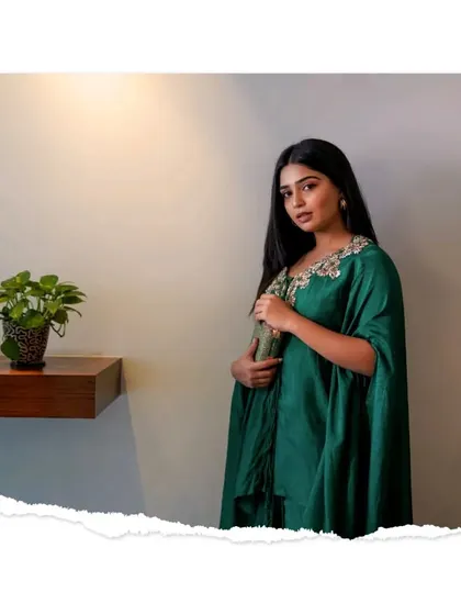 A simple and elegant portrait in a green kaftan, with a clean background that emphasizes her natural beauty.