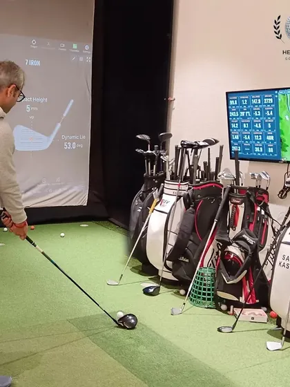 A wider view of the studio, showing the client at address, the data screen, and the array of clubs ready for testing.
