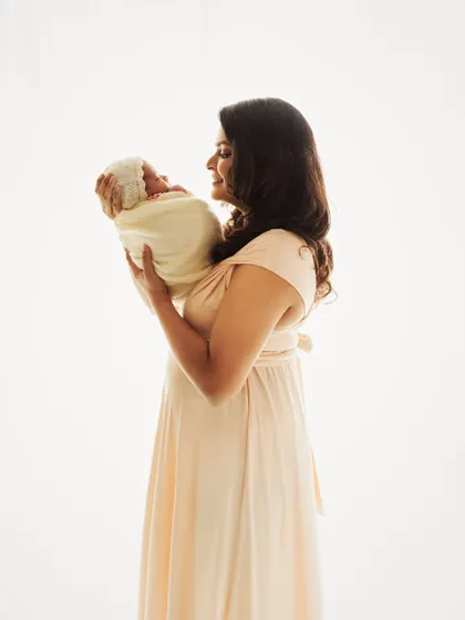 A beautiful solo portrait of a new mother holding her baby. The soft, high-key lighting creates an angelic and timeless feel.