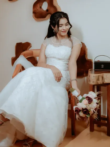 A beautiful portrait of a Christian bride seated, her elegant white gown and bouquet on full display.