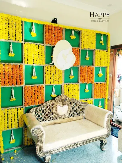 A classic marigold backdrop with a central Ganesha cutout, perfect for a naming ceremony or any auspicious beginning. The ornate sofa completes the setup for a beautiful photo opportunity.