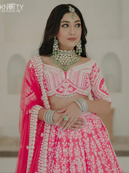 A close-up portrait of the bride, showcasing her beautiful off-shoulder blouse and contrasting green jewelry. We focus on the fashion and styling details.