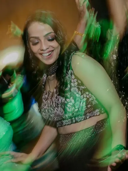 A guest dancing with joy, captured with a green-lit motion blur effect that adds to the energy of the sangeet night.