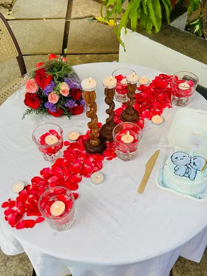 The complete table setup for a romantic meal, with candles, a flower bouquet, and a personalized cake, all ready for the couple to enjoy.