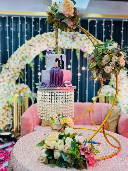 A beautiful cake table setup that also serves as a photo corner. The suspended cake stand is a unique touch, framed by a floral arch and a comfortable sofa for the couple.